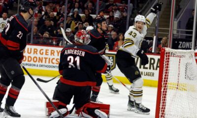 Boston Bruins' Danton Heinen (43) celebrates after his goal near Carolina Hurricanes goaltender Frederik Andersen (31), Brett Pesce (22) and Jake Guentzel (59) during the first period of an NHL hockey game in Raleigh, N.C., Thursday, April 4, 2024.