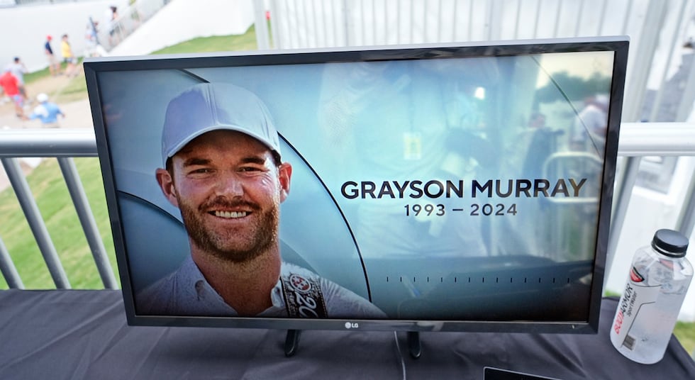 A golf television broadcast is played at the broadcast tent showing a photo of Grayson Murray...