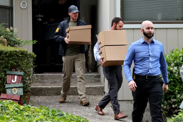 FBI agents carry boxes out of the house associated with...