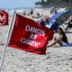 Lifeguards post hazardous rip current flags in the sand on March 22, 2022, at Midtown Beach in Palm Beach, Florida, after making a rescue in the rough surf.