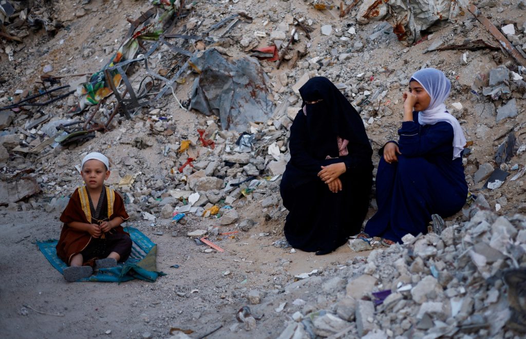 Palestinians hold Eid al-Adha prayers by the ruins of al-Al Rahma mosque destroyed by Israeli air strikes, in Khan Younis,...