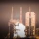 Flames and smoke billow from underneath a rocket as it lifts off from a launch pad.