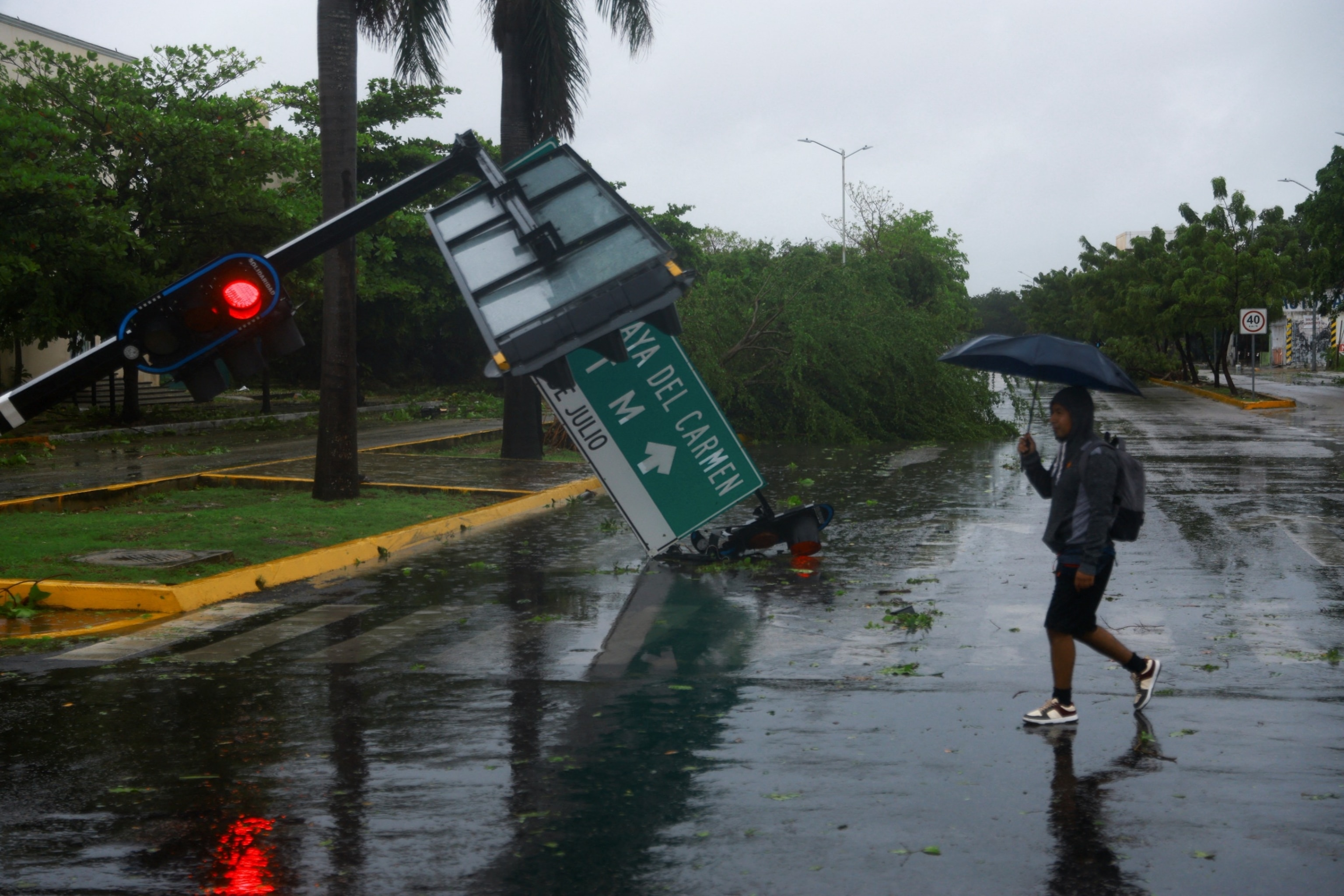 PHOTO: A man passes by a traffic signal toppled by heavy winds and rain caused by Hurricane Beryl, a Category 2 storm, in Playa del Carmen, Mexico, July 5, 2024. 