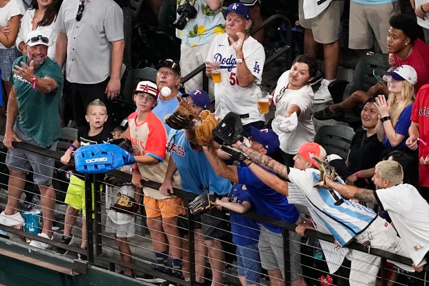 Fans reach to catch a home run ball hit by...