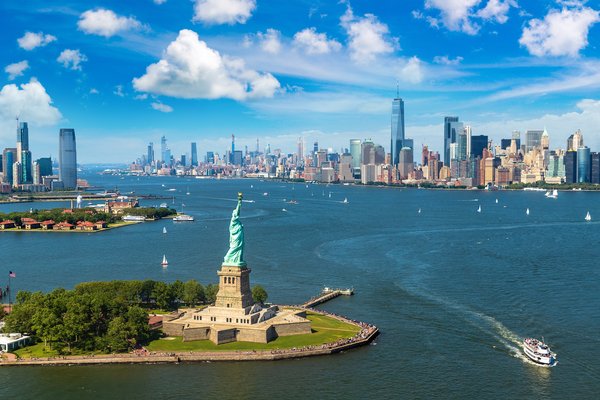 An aerial shot of the Statue of Liberty and New York Harbor and some of the city.