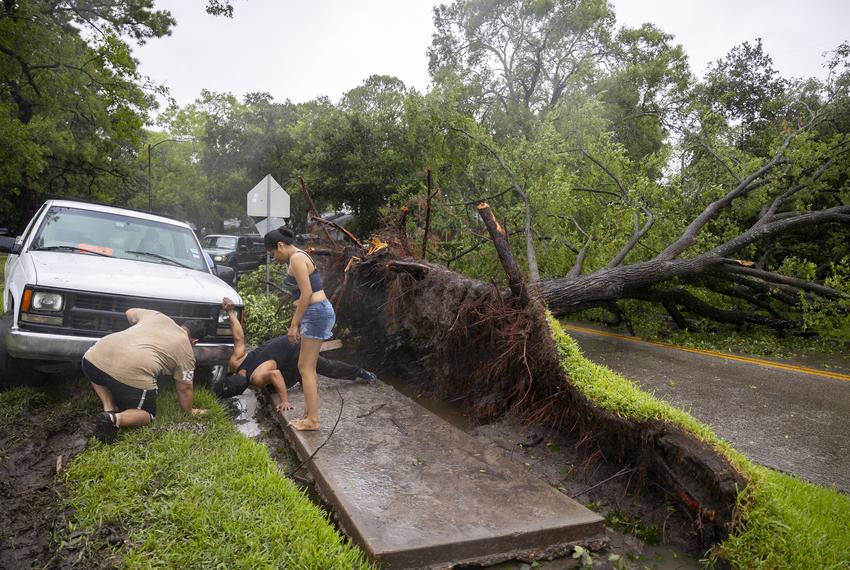 People work to get a truck out of the mud from a downed tree off Willowbend Boulevard after Hurricane Beryl brought strong winds and rain on Monday, July 8, 2024, in Houston.