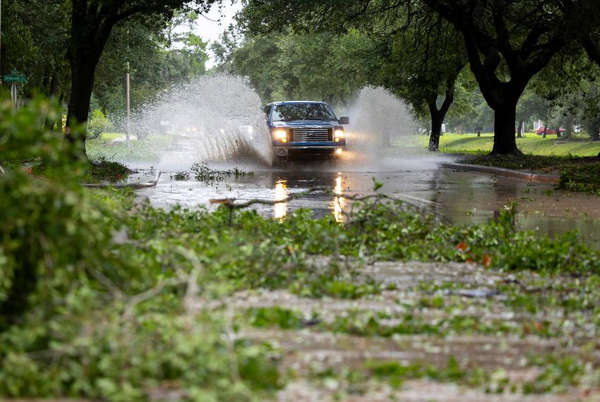 A truck drives through water and downed branches from Hurricane Beryl on Monday, July 8, 2024, in Houston.